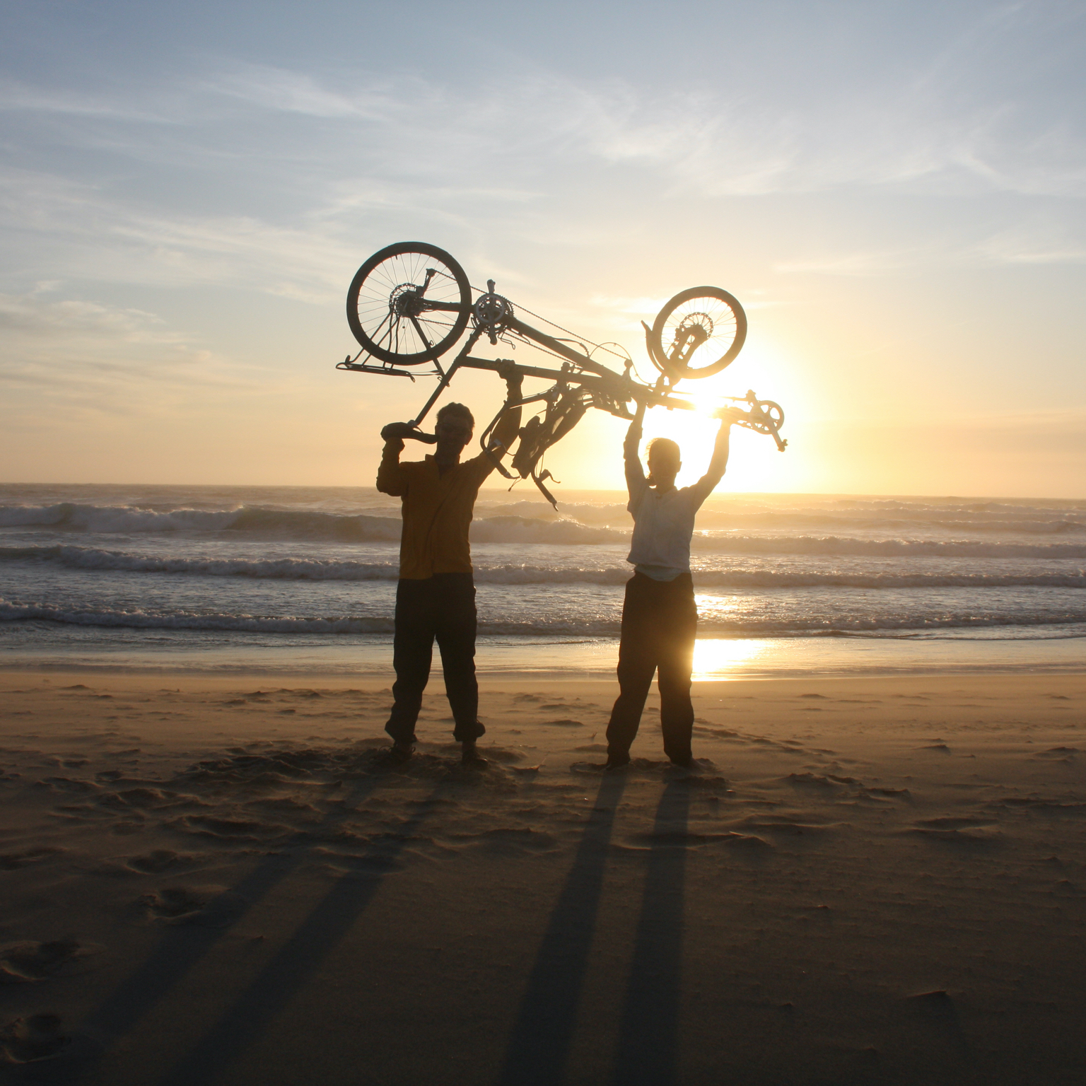 Jillian and Kyle holding up their tandem bicycle at the end of the bike trip